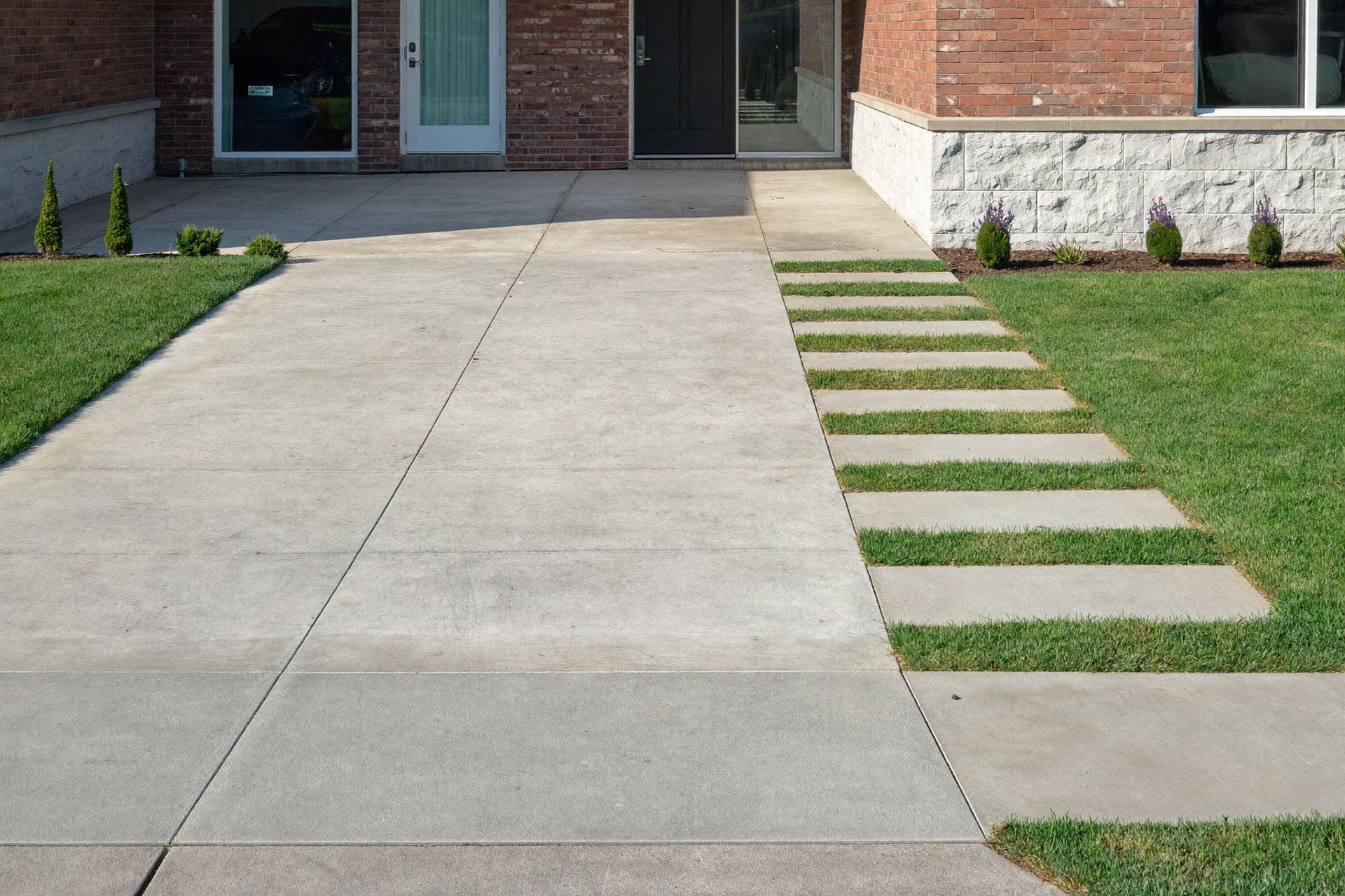 Clean concrete driveway leading to a brick suburban home in Texas